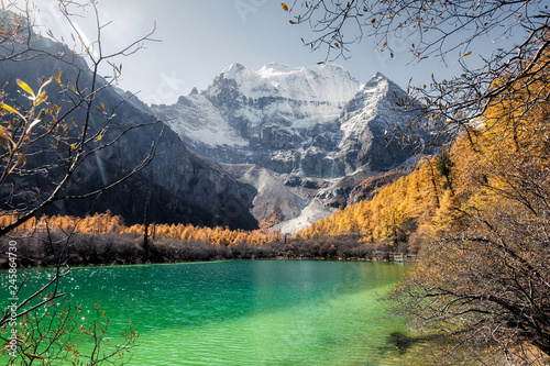 Fototapeta Naklejka Na Ścianę i Meble -  Xiannairi mountain on emerald lake with golden pine forest in autumn