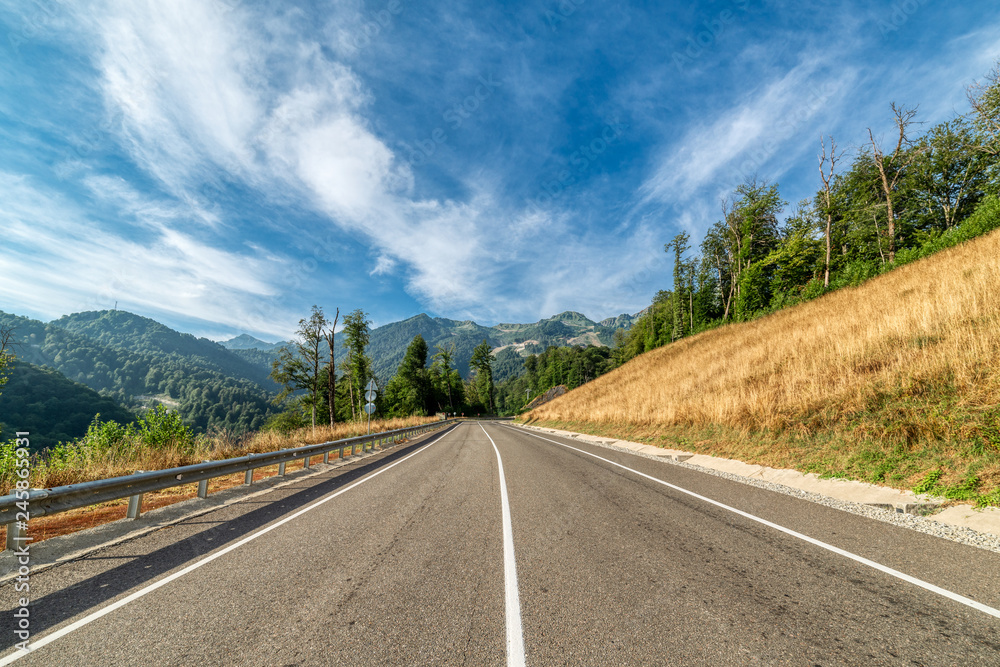 Asphalt mountain road. Blue sky with white clouds. Asphalt mountain road. Blue sky with white clouds.