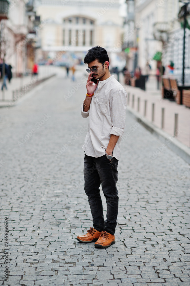 Stylish indian model man in casual clothes and sunglasses posed outdoor at  street of India and speaking on mobile phone. Photos | Adobe Stock