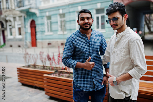 Two indian mans, wear on casual clothes, posed outdoor at street of India. They shows thumb up. photo