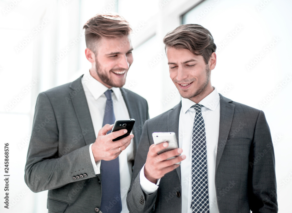 two employees using their smartphones on a work break two employees using their smartphones on a work break