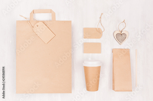 Coffee shop template for branding identity - brown paper cup with blank bag, packet, label, card, wooden heart on white wood board, top view.