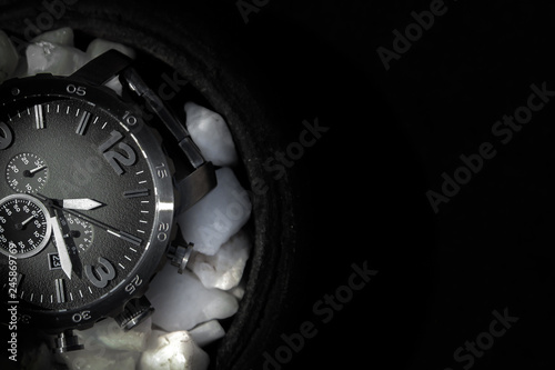 black colour watch on white stones in a black background