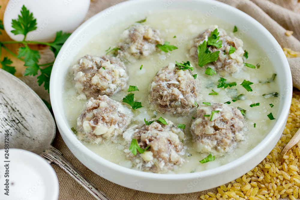 Armenian white sour soup on chicken broth with meatballs, bulgur and green parsley Armenian white sour soup on chicken broth with meatballs, bulgur and green parsley