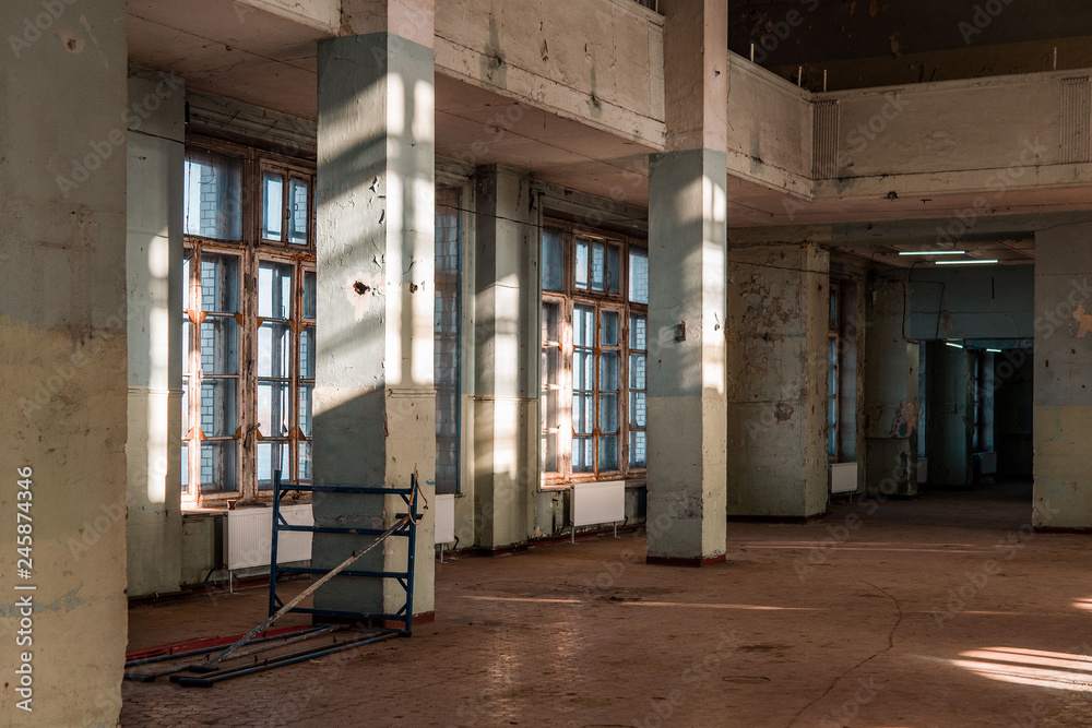 Old abandoned building of the Soviet manufactory. Empty room with columns. Daylight