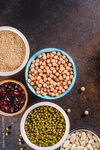 Top view on bowls with various grains on a textured dark background.