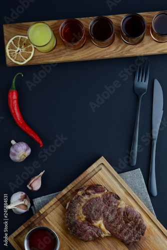 Wooden board with shots near red pepper, cutlery and garlic 