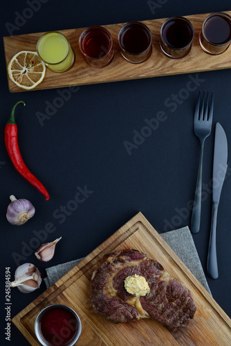 Wooden chopping board near pepper, cutlery and garlic