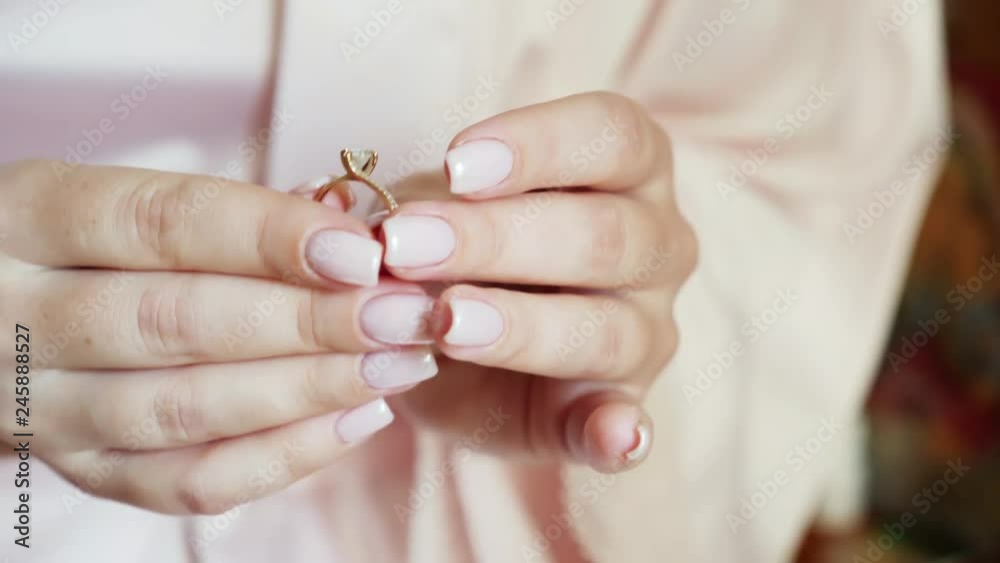 Girl with beautiful nail polish examines a diamond ring holding it in his hands Girl with beautiful nail polish examines a diamond ring holding it in his hands