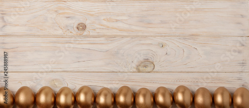 Happy easter! Easter decor and Easter eggs of golden color on a light wooden background.
