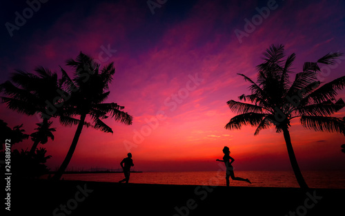 Silhouette of couple on tropical beach during sunset on background of palms and sea