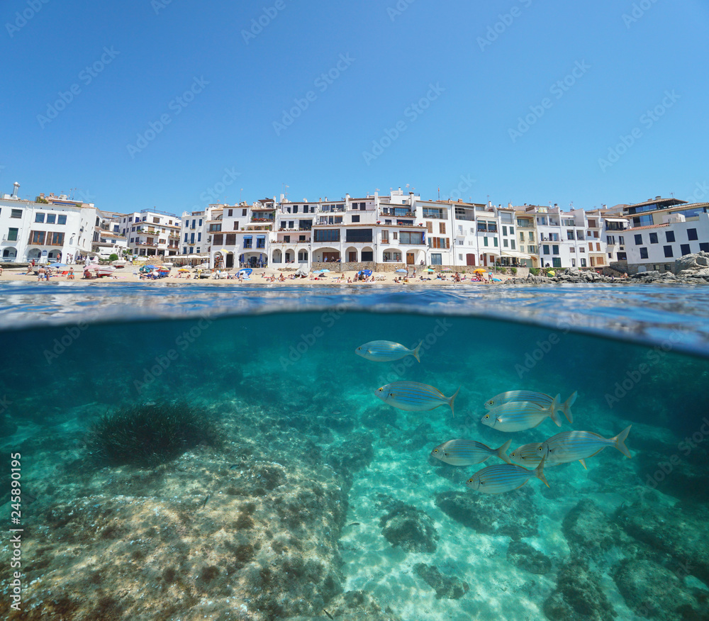 Spain Mediterranean coastal village with fish underwater sea, Calella de Palafrugell, Costa Brava, Catalonia, split view half over and under water