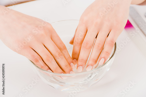 Partial view of manicurist with beautiful fingers taking nail bath