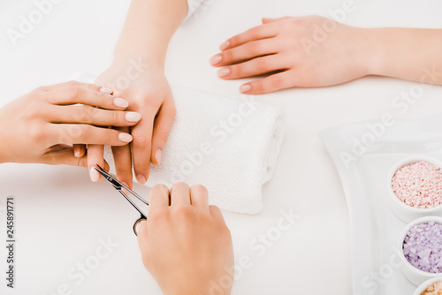 Cropped view of manicurist cutting cuticles with scissors