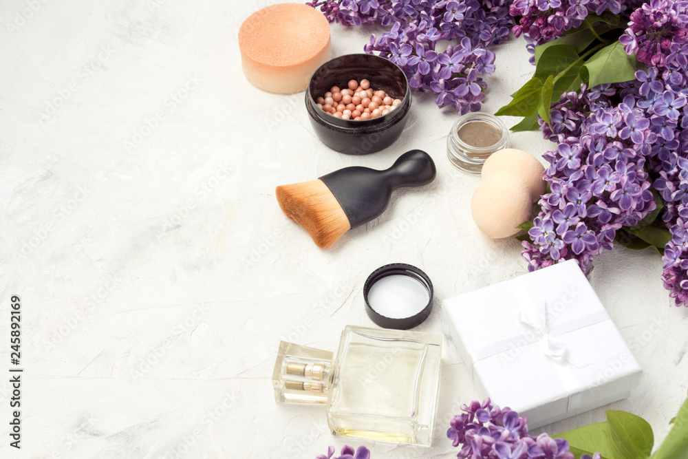 Accessories for make-up and skin care, perfumes, lilacs on a light stone background Accessories for make-up and skin care, perfumes, lilacs on a light stone background
