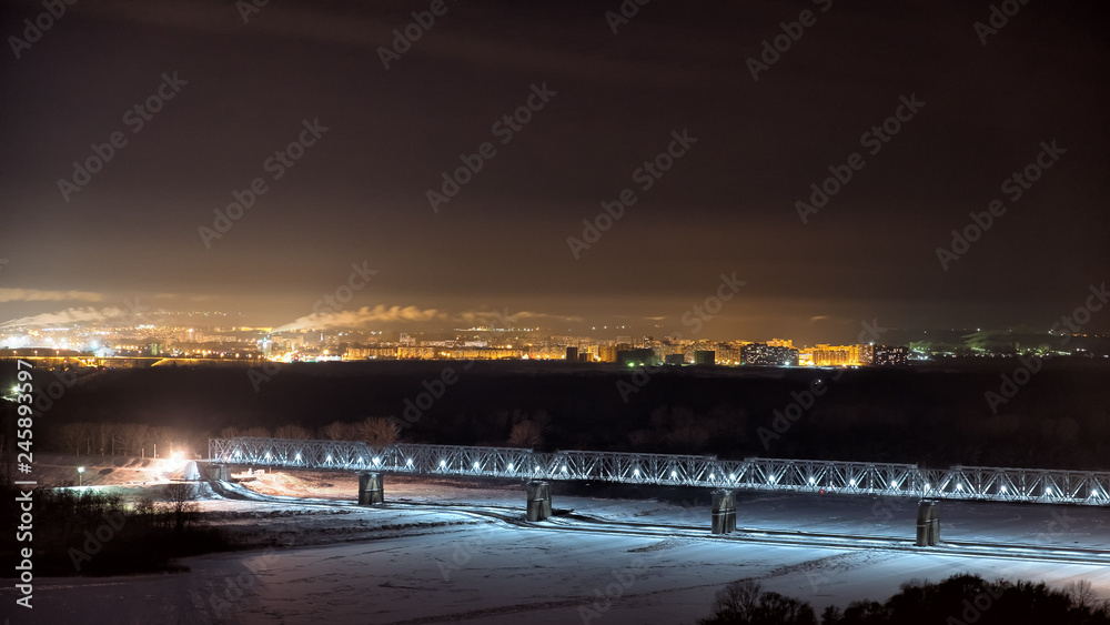trans siberian railway bridge over frozen river with scenic city lights skyline background on cold russian winter night time transportation cityscape landscape wonderland