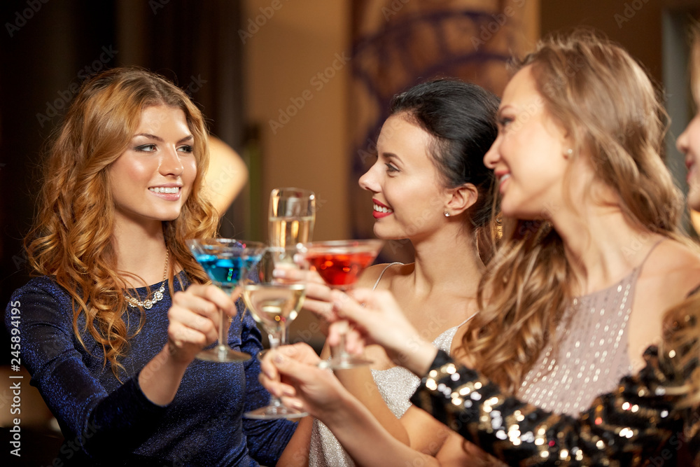 celebration, bachelorette party and holidays concept - happy women or female friends clinking glasses at night club