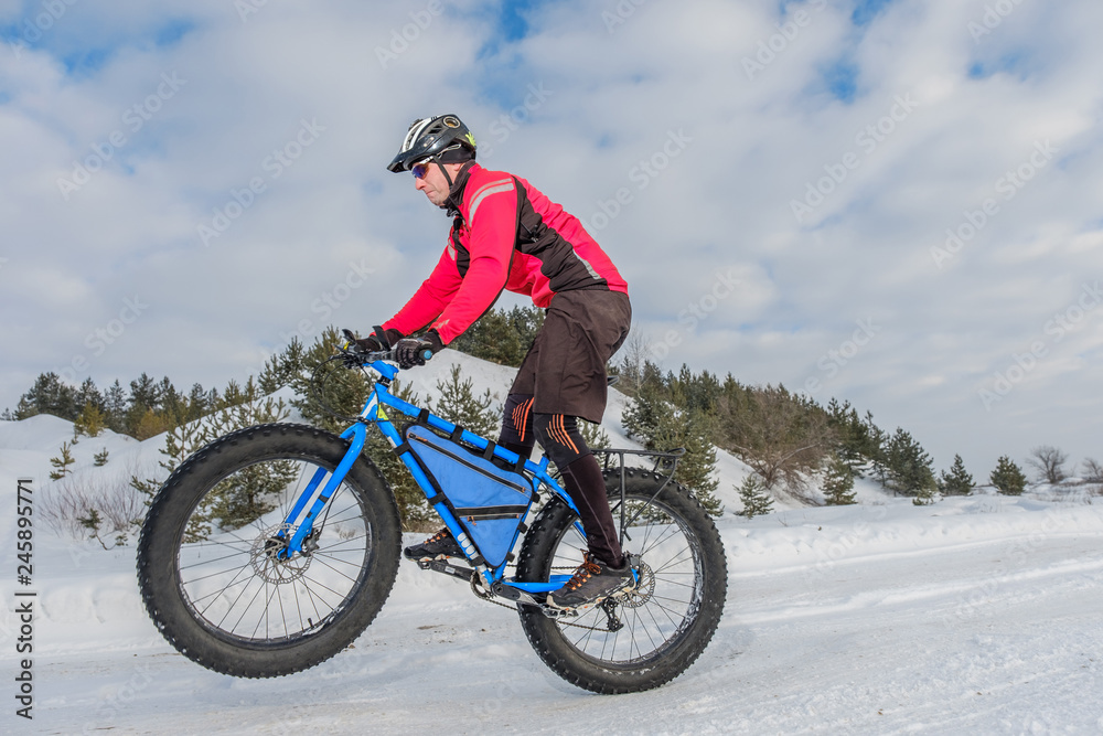 A young man riding fat bicycle in the winter. Fat tire bike.	