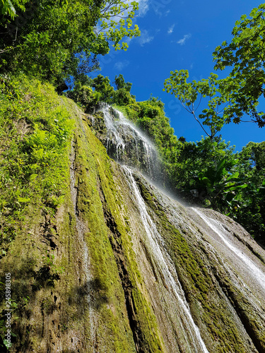 under beautiful tropical waterfall with a lot of moss on the rock in dominican forest