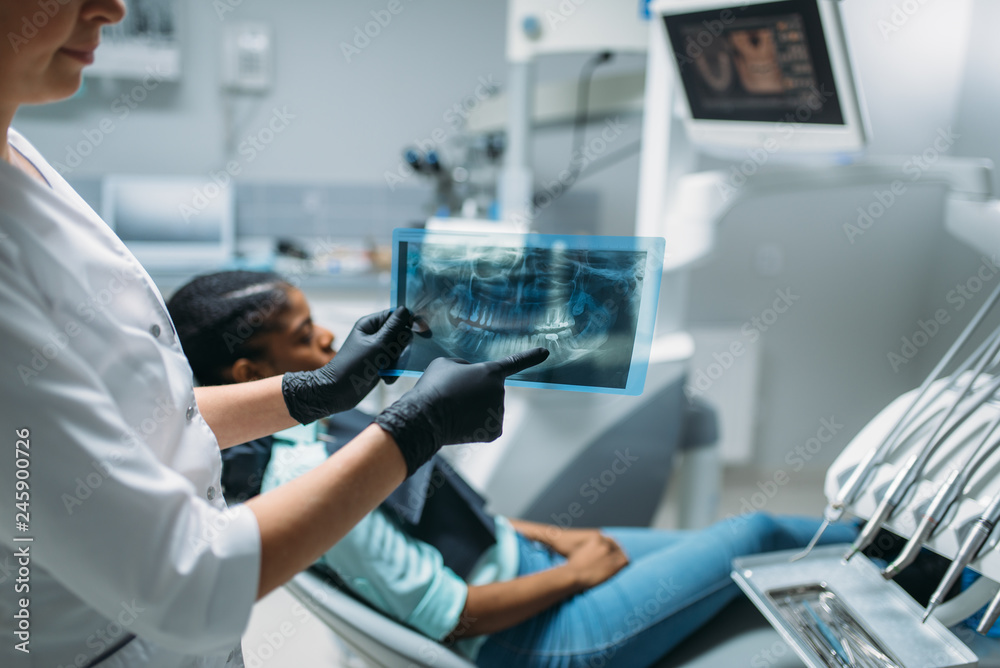 Naklejka premium Female dentist shows problem on x-ray picture