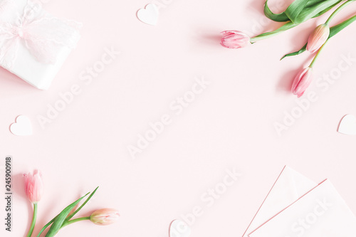 Valentine's Day composition. Tulip flowers, envelope on pastel pink background. Valentines day, mothers day, womens day concept. Flat lay, top view, copy space