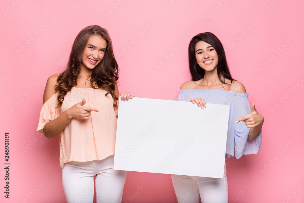 Happy girl friends holding blank advertisement board Happy girl friends holding blank advertisement board