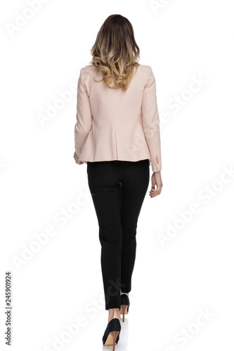 Fotografia rear view of young businesswoman wearing pink suit stepping