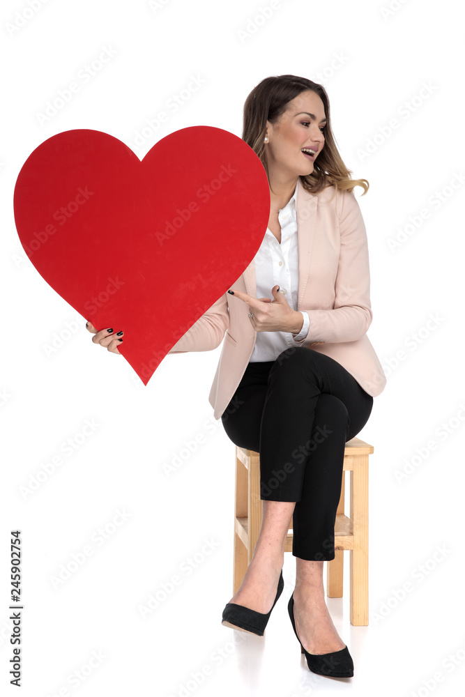 attractive businesswoman holds valentine day heart and points to side attractive businesswoman holds valentine day heart and points to side