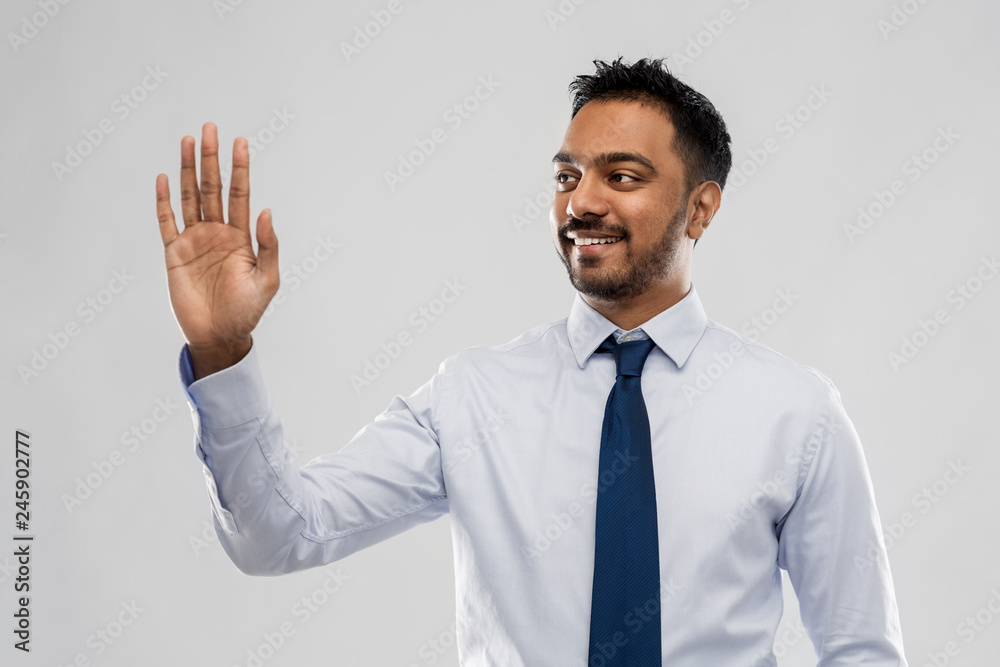 business, office worker and people concept - smiling indian businessman in shirt with tie working with virtual screen over grey background business, office worker and people concept - smiling indian businessman in shirt with tie working with virtual screen over grey background