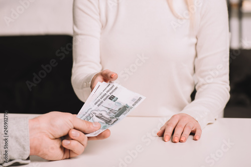 cropped shot of man giving russian rubles banknotes to woman