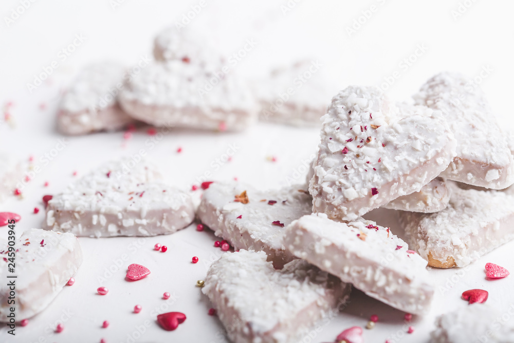  Valentine's day white coconut heart shaped cookies with red and pink heart sprinkles. Copy space