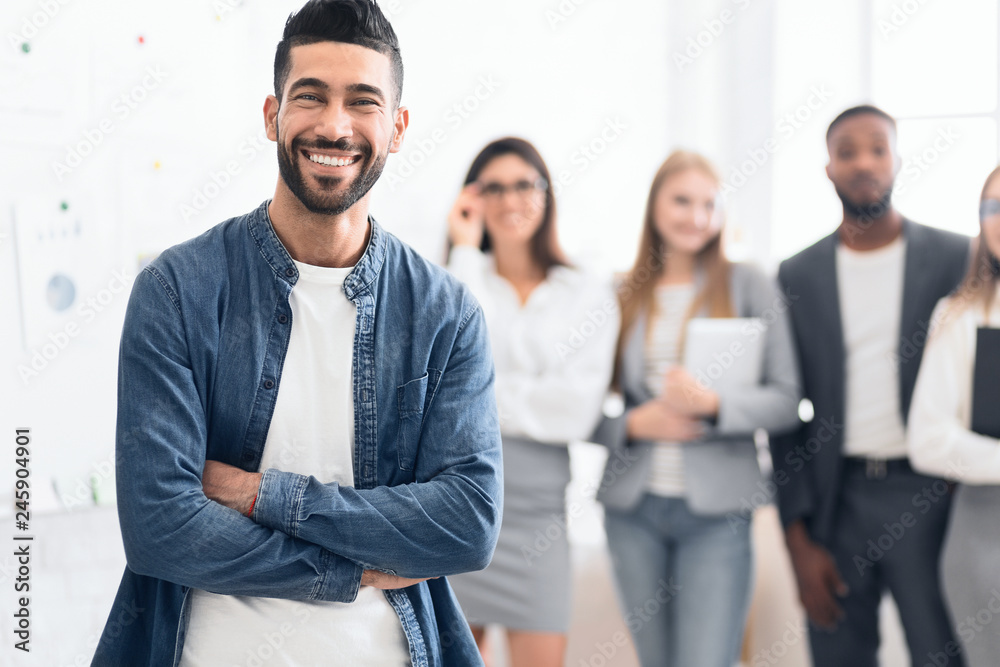 Man standing in office with colleagues on background Man standing in office with colleagues on background