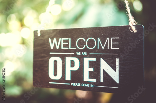 A business sign that says open on cafe or restaurant hang on door at entrance.