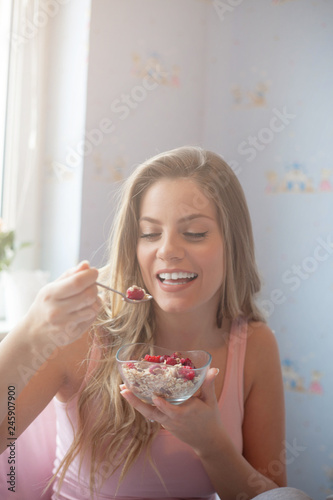Joyful woman eating cereal in the morning.