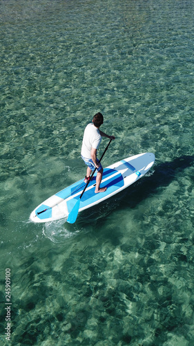 Aerial drone bird's eye view photo of man exercising Stand Up Paddle surf board or SUP in tropical exotic bay with emerald clear sea © aerial-drone