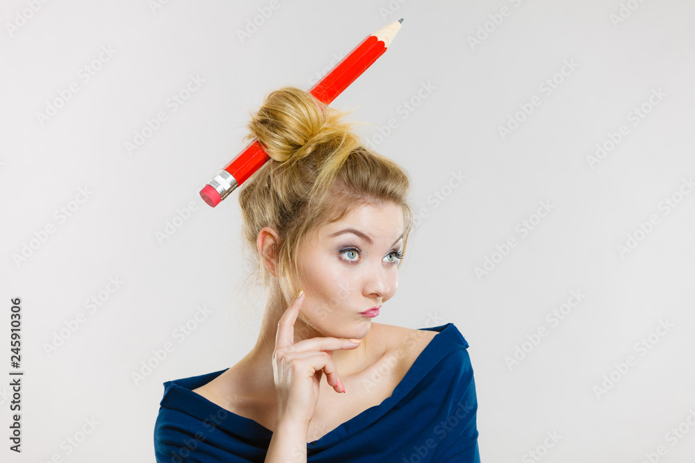 Thinking blonde woman having big pencil in hair Thinking blonde woman having big pencil in hair