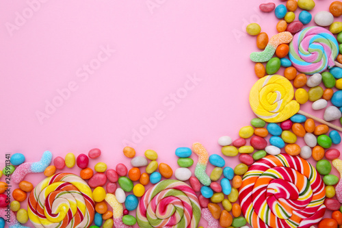 Colorful lollipops and different colored round candy on pink background