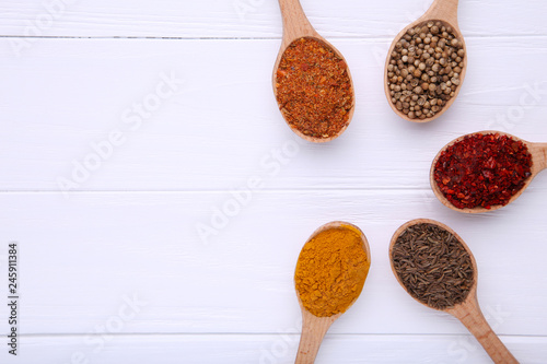 Spices mix on wooden spoons on a white wooden background. Top view