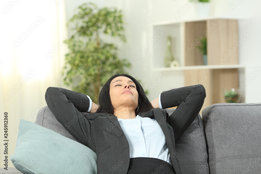 Office worker rests after work sitting on a couch in the living room at home Office worker rests after work sitting on a couch in the living room at home