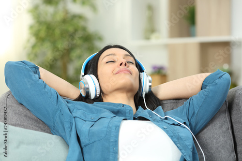 Relaxed woman resting listening to music on a couch