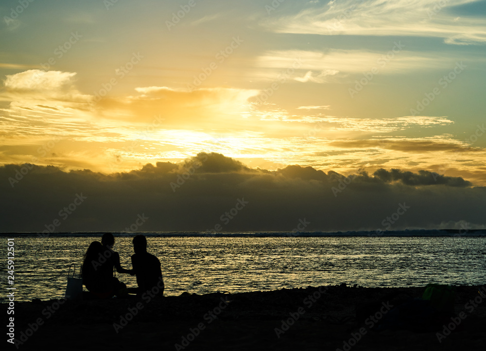 Three people having a sunset picknick on the beach in Black River, Mauritius