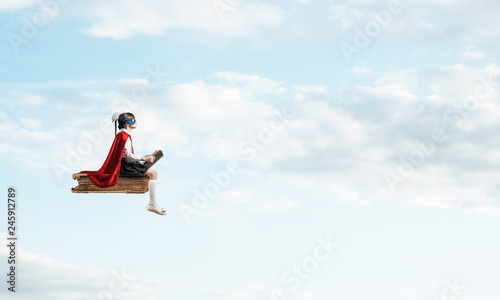 Girl power concept with cute kid guardian against cloudscape background © adam121