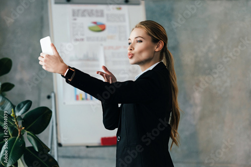Young businesswoman taking selfie with duck face