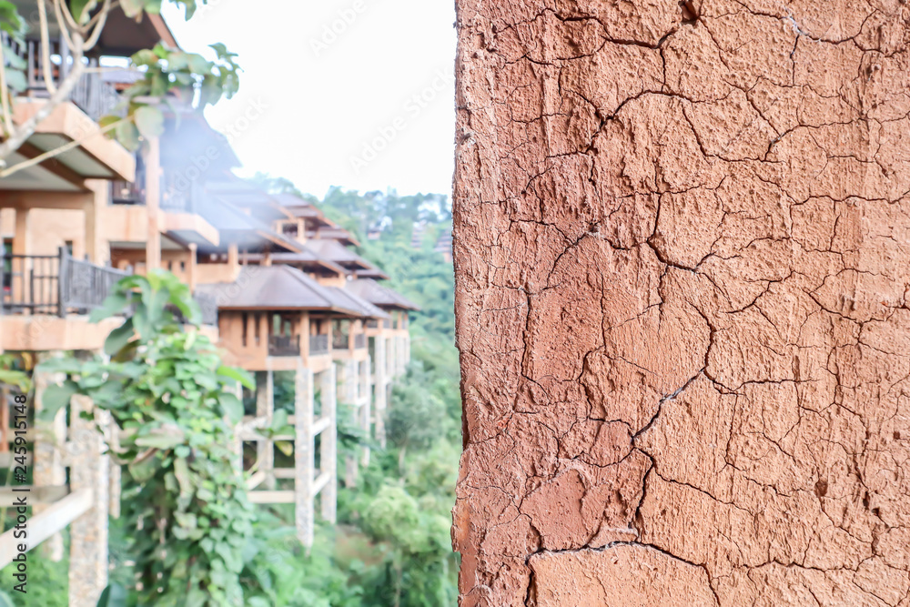 Fototapeta premium Closeup on earth wall made of local clay and grass with blurry view of sustainable building in Northern part of Thailand.
