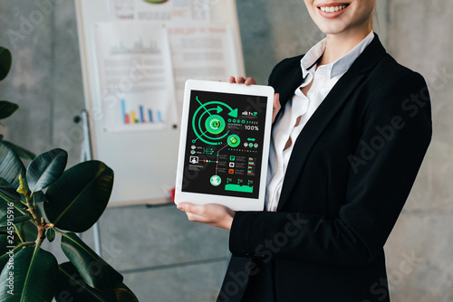 Cropped view of pretty smiling businesswoman holding digital tablet with inphographics on screen photo