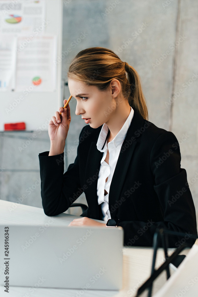 Thoughtful businesswoman sitting at work desk and touching head with pencil Thoughtful businesswoman sitting at work desk and touching head with pencil