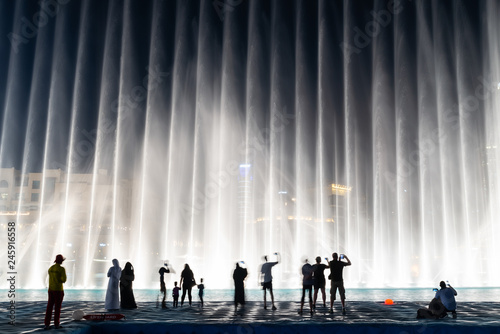 Silhouettes of people enjoying the fountain show in Dubai at night, United Arab Emirates