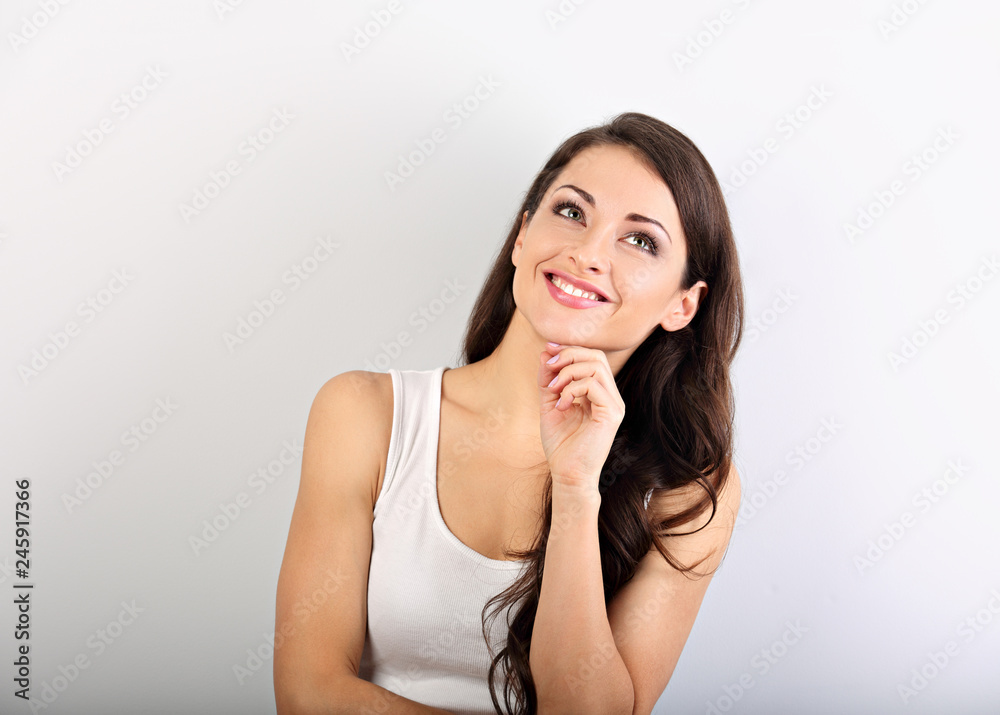 Beautiful young happy casual woman with finger under the face thinking and looking up in white shirt and long hair. Closeup portrait Beautiful young happy casual woman with finger under the face thinking and looking up in white shirt and long hair. Closeup portrait