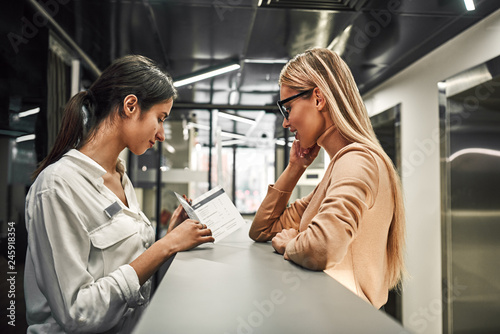 Young woman at reception or front office asking service catalog of hotel