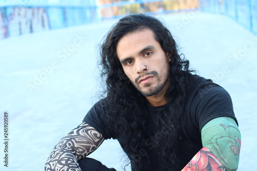 Tough looking hispanic man with long hair and tattoos